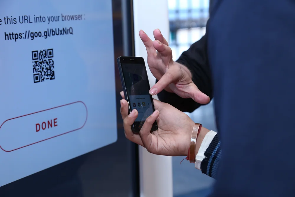A traveller completing the flow at the kiosk, phone in hand ready to receive the playlist by SMS.