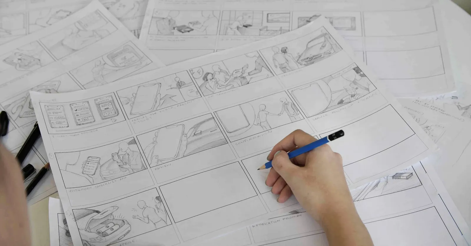 Hand-drawn service-journey storyboard frames spread across a table, sketched in pencil.